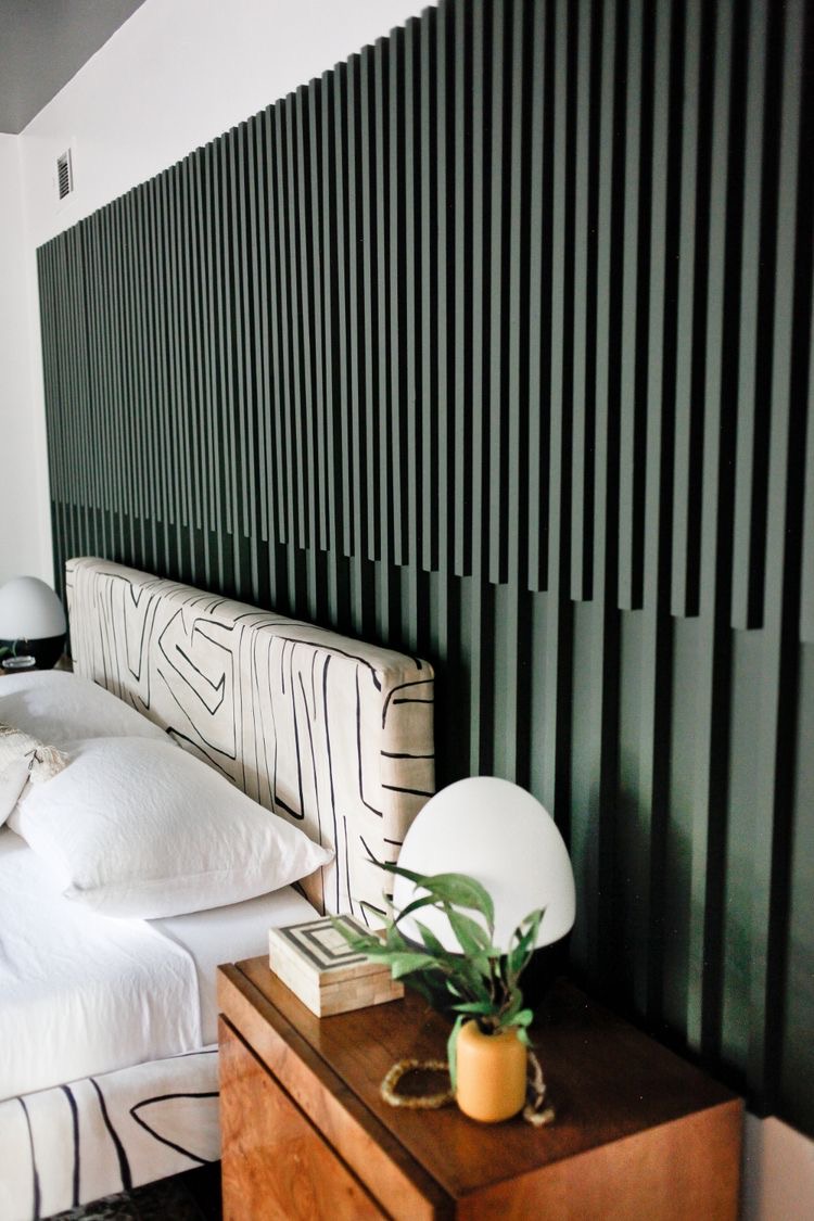 Bedroom with deep green vertical wood slat accent wall behind a patterned headboard — a bold color accent wall idea.