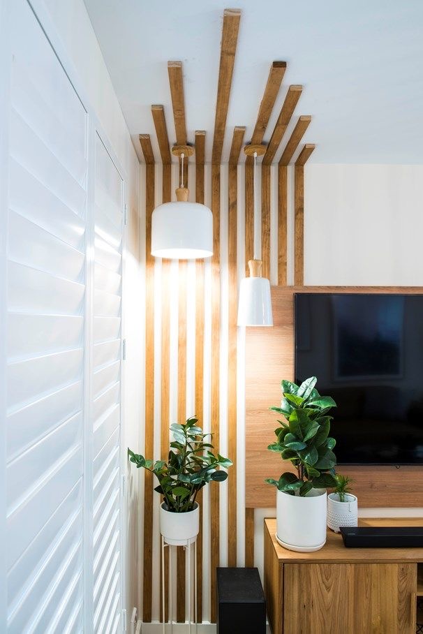 Partial wood slat accent wall with integrated pendant lighting around a TV — a layered accent wall idea with built-in light fixtures.