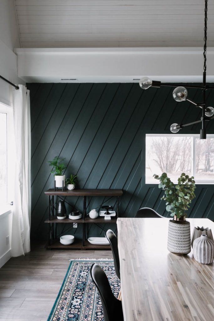 Home office with dark green diagonal shiplap accent wall behind a shelf — a modern accent wall idea using angled paneling.