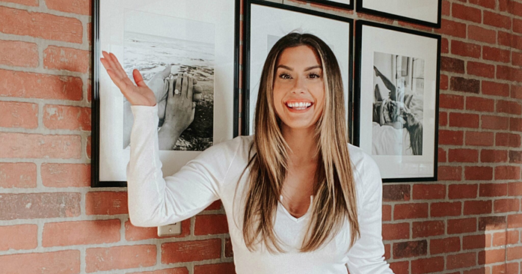Liz Lovery in front of an exposed brick accent wall — designer's guide to 15 accent wall ideas to elevate any room.