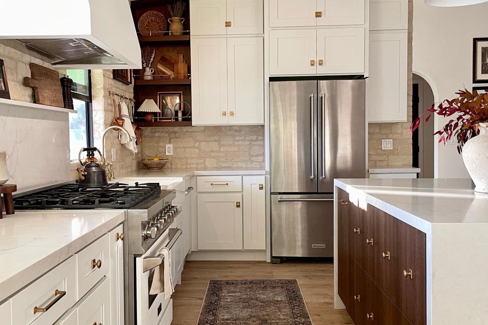Walnut wood-panel open shelves with a brass gallery rail in Liz Lovery's white kitchen