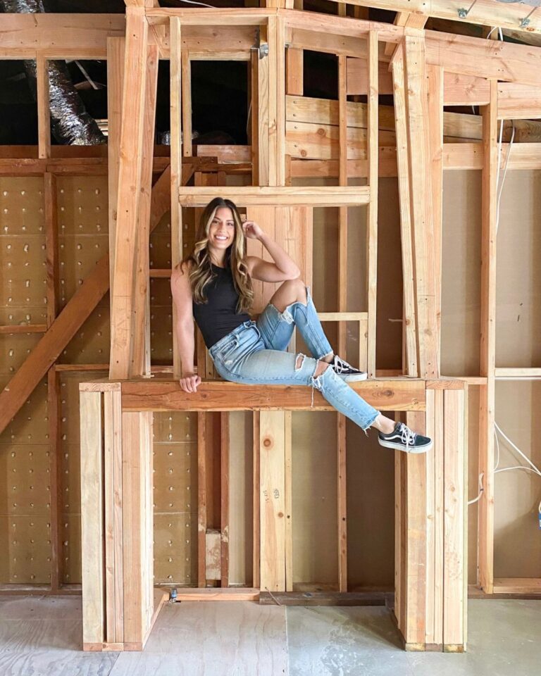 Liz Lovery sitting on the framing of a home renovation in progress.