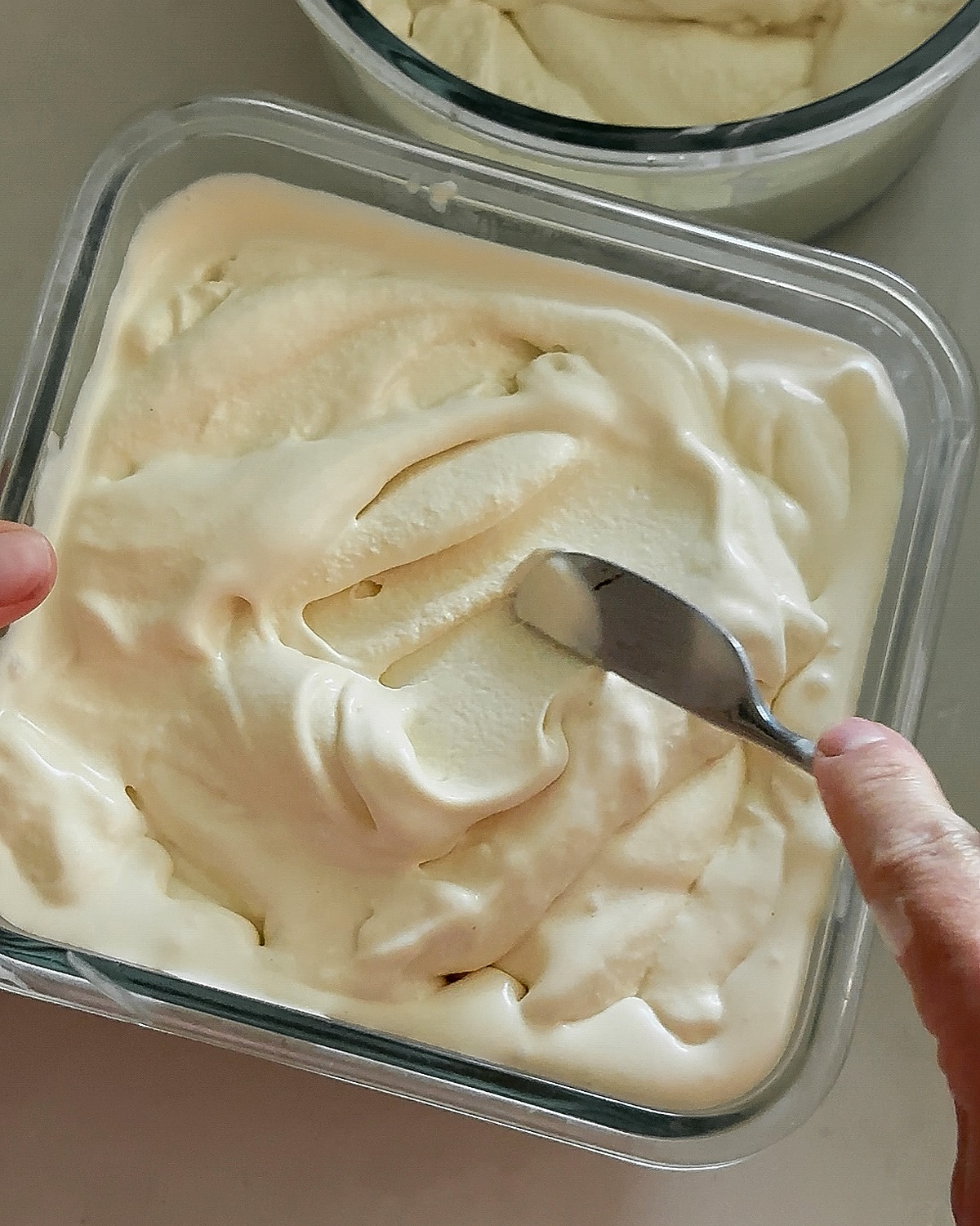 Freshly churned homemade vanilla ice cream smoothed into a freezer storage container