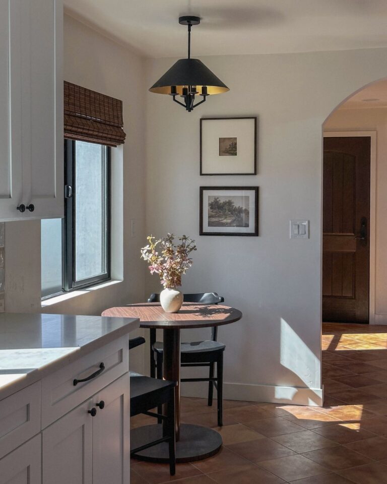 The Adobe Project kitchen breakfast nook with black pendant light, arched doorway, Saltillo tile floors, and bistro table
