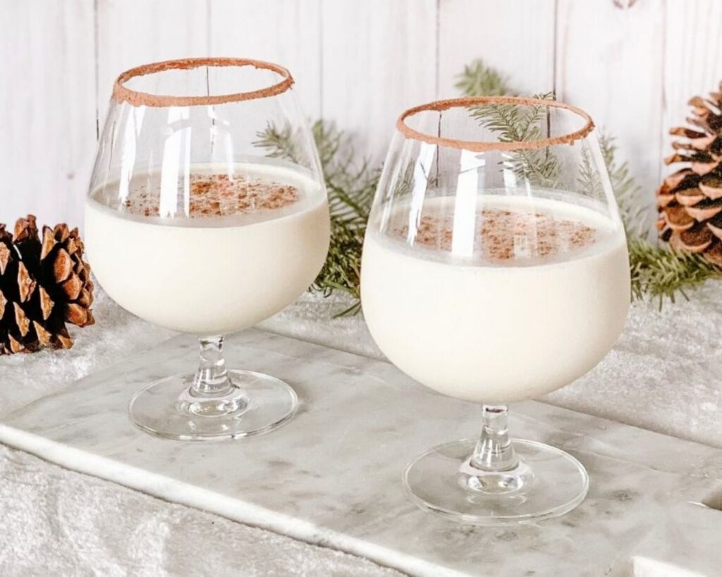 Creamy Brandy Alexander dessert cocktails served in snifter glasses with cinnamon-sugar rims and freshly grated cinnamon.
