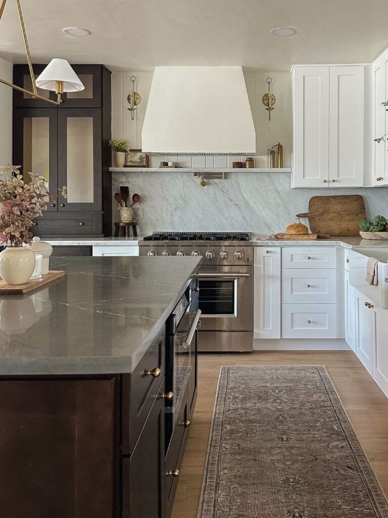 The Paisley Project kitchen renovation with dark island, brass hardware, and custom white cabinetry
